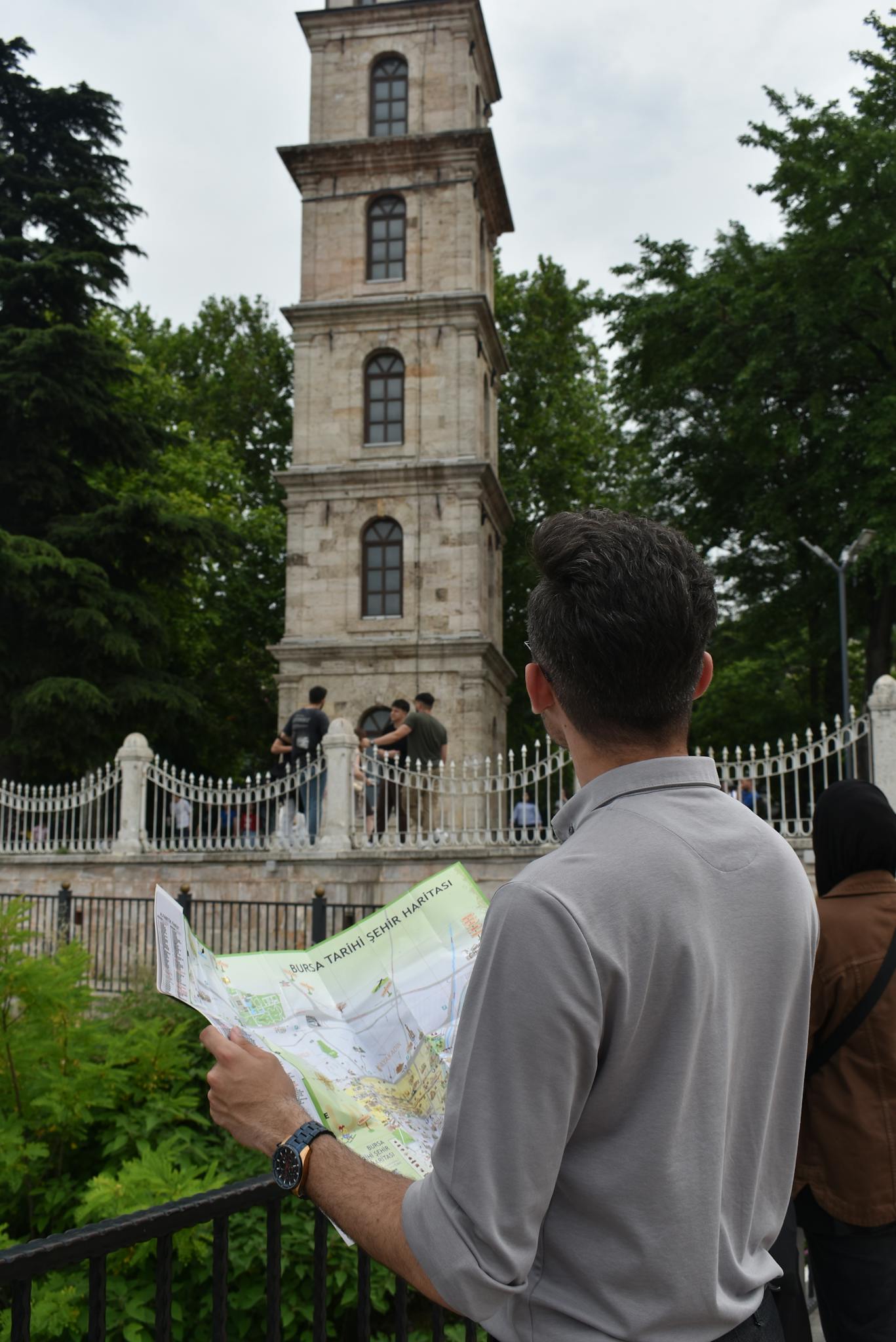 A tourist holding a map in front of the Tophane Clock Tower, Bursa, Türkiye.