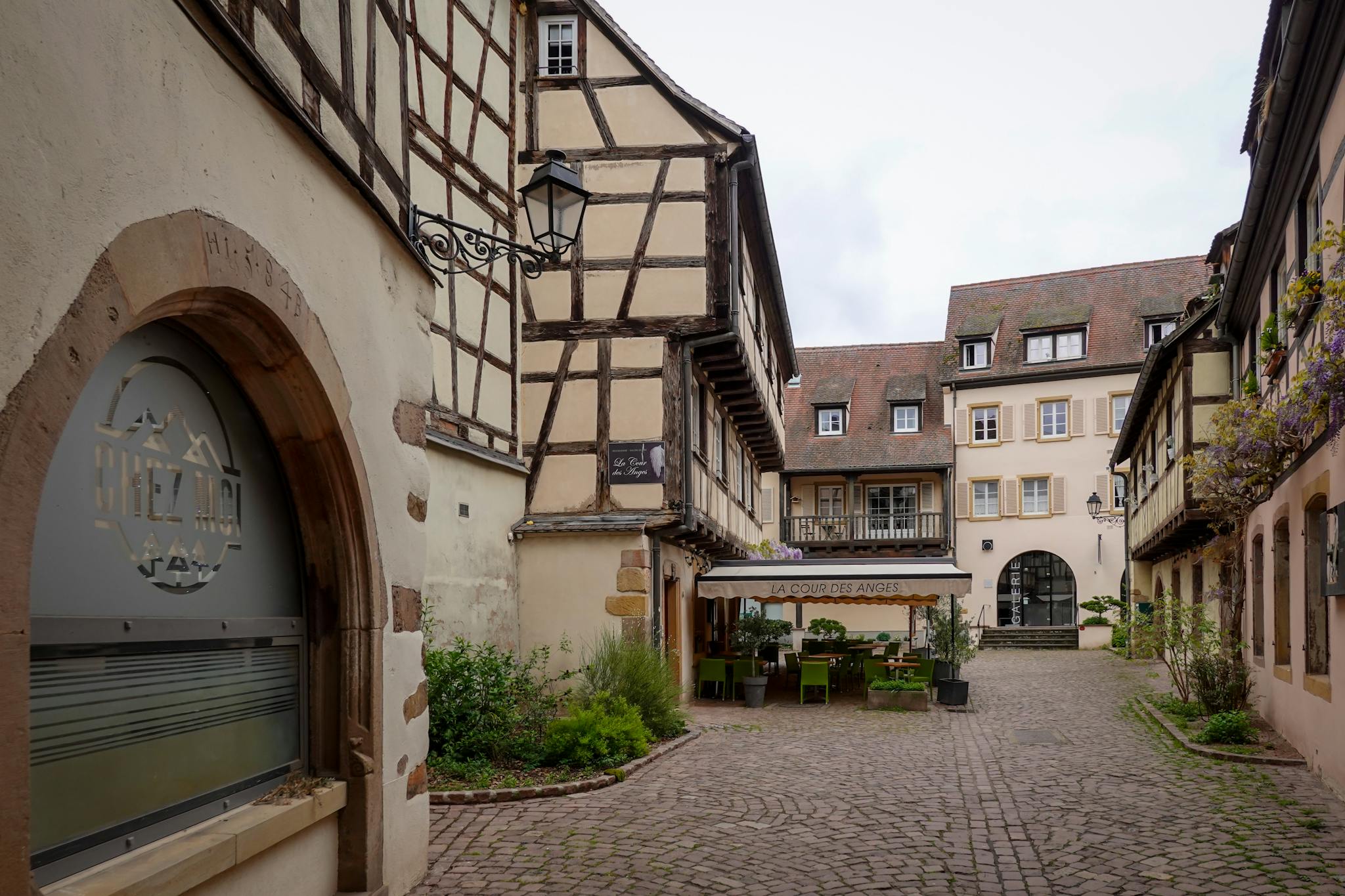 Explore a quaint European courtyard showcasing traditional timber-framed architecture and a cozy cafe setting.