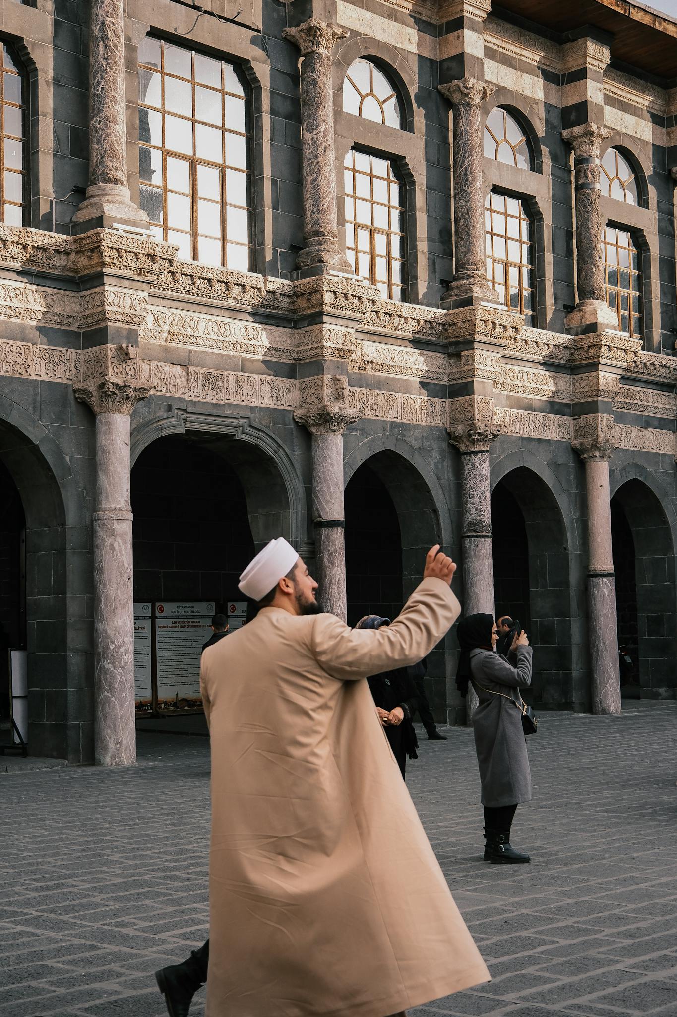 Tourists admire and photograph historic architecture with detailed stonework.